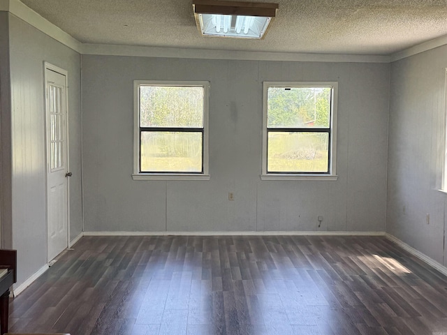 empty room featuring dark wood-type flooring, a textured ceiling, and baseboards