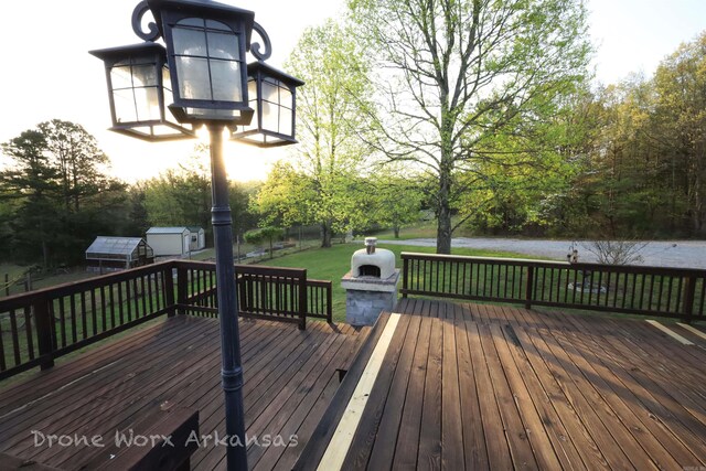 wooden terrace with a storage unit, a lawn, and an outbuilding