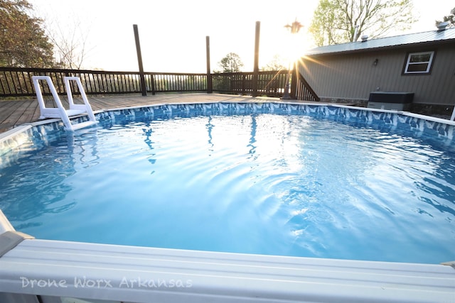 view of pool with a fenced in pool, central AC unit, and a deck