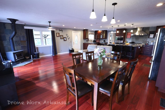 dining room with recessed lighting, a wood stove, visible vents, baseboards, and dark wood-style flooring
