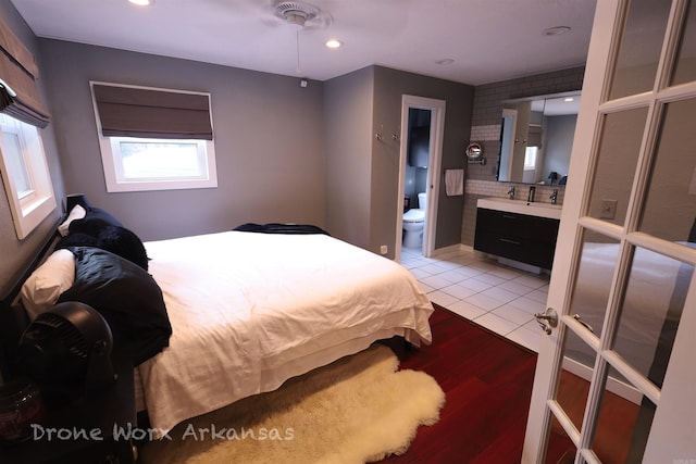bedroom with connected bathroom, recessed lighting, a sink, and light wood-type flooring