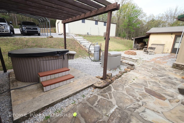 view of patio featuring a fire pit, a hot tub, and a carport
