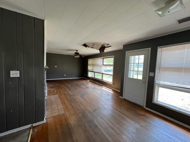 interior space with baseboards, visible vents, hardwood / wood-style flooring, and ceiling fan