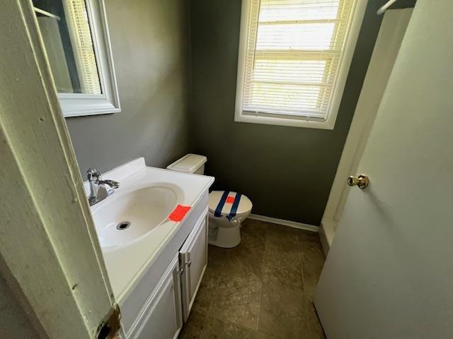 bathroom with baseboards, vanity, and toilet