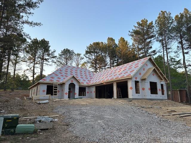 property in mid-construction featuring a garage and gravel driveway