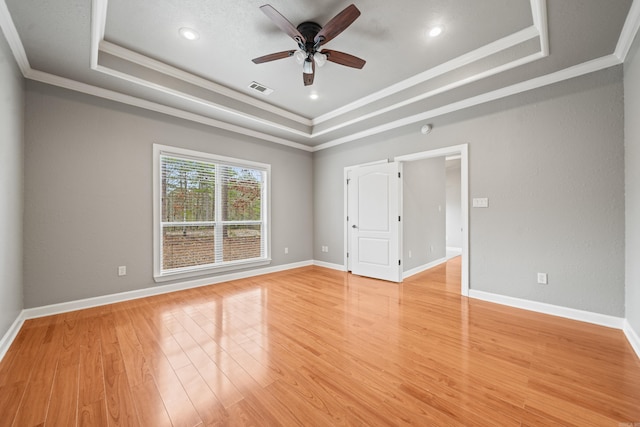 unfurnished room with a raised ceiling, visible vents, a ceiling fan, and ornamental molding