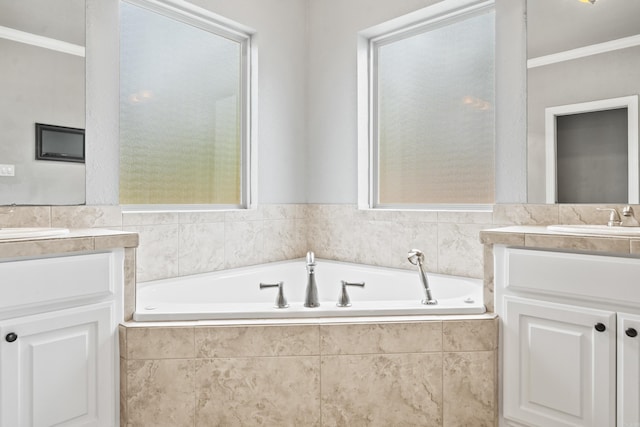 bathroom featuring a bath, two vanities, ornamental molding, and a sink