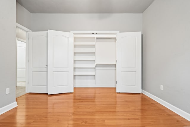 unfurnished bedroom with baseboards, light wood-style floors, and a closet