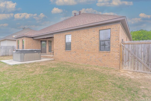 6037 Beaver Creek Ln, Jones Creek, AR 72404 - rear view of property featuring a lawn, fence, a hot tub, a patio, and brick siding
