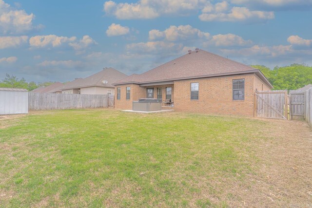 6037 Beaver Creek Ln, Jones Creek, AR 72404 - back of house with a fenced backyard, a gate, brick siding, a lawn, and a hot tub
