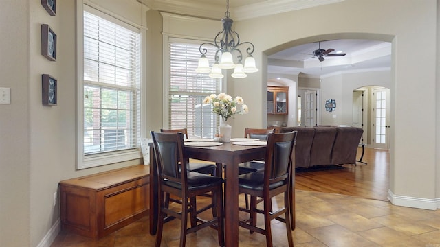 dining room featuring baseboards, arched walkways, ornamental molding, and ceiling fan with notable chandelier
