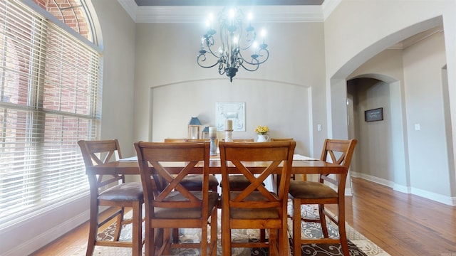 dining space featuring plenty of natural light, light wood-style flooring, arched walkways, and an inviting chandelier