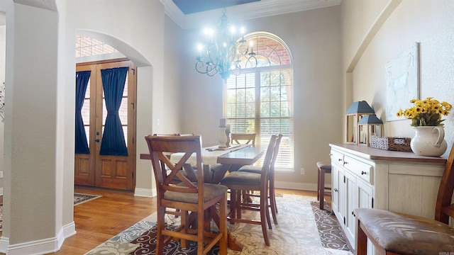 dining area featuring a notable chandelier, arched walkways, ornamental molding, and a healthy amount of sunlight