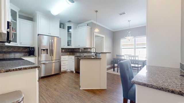 kitchen with a sink, decorative backsplash, glass insert cabinets, stainless steel appliances, and a peninsula