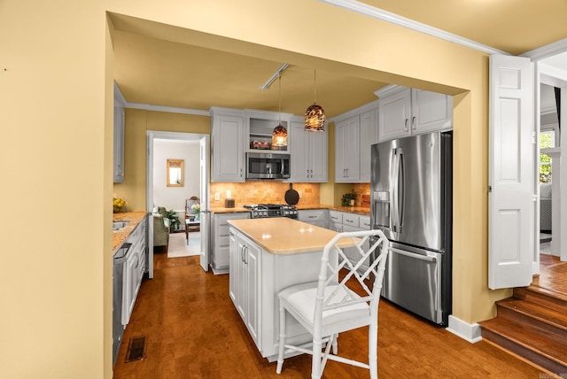 5715 Hawthorne Rd, Little Rock, AR 72207 - kitchen with a center island, decorative backsplash, light countertops, appliances with stainless steel finishes, and hanging light fixtures