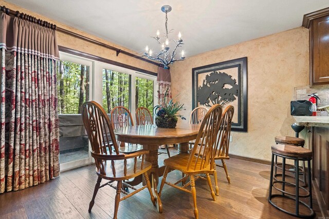 dining space with a notable chandelier, wood-type flooring, baseboards, and a textured wall