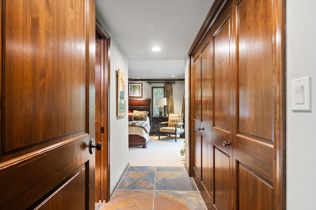 hallway with recessed lighting, dark colored carpet, and stone finish flooring