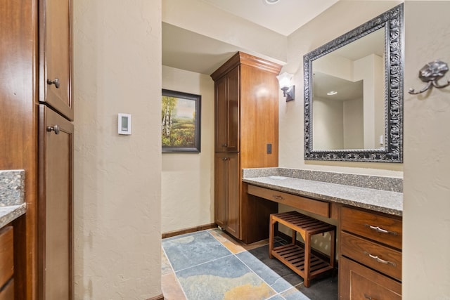 bathroom with baseboards, a textured wall, and vanity