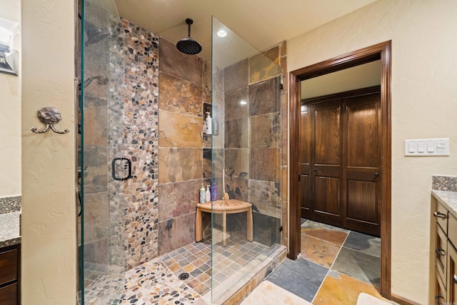bathroom with stone finish flooring, vanity, and a stall shower