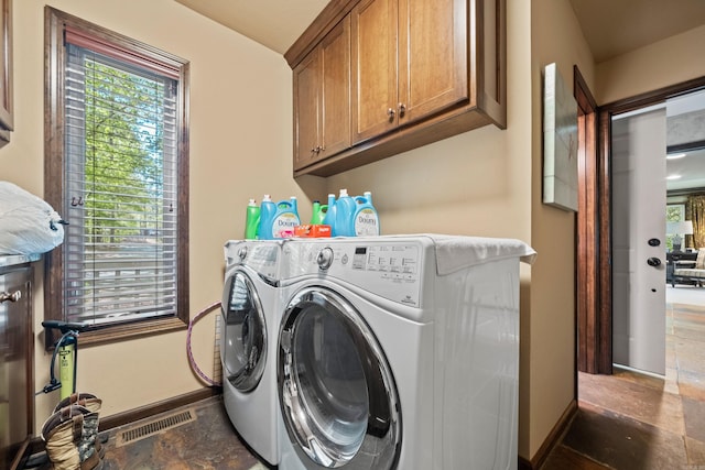laundry room with washing machine and clothes dryer, baseboards, visible vents, stone finish floor, and cabinet space