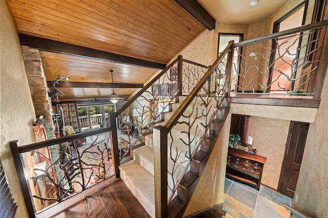 stairway featuring ceiling fan, wooden ceiling, a textured wall, and vaulted ceiling with beams