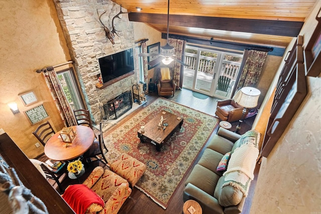 living area with lofted ceiling, a stone fireplace, wood finished floors, and wood ceiling