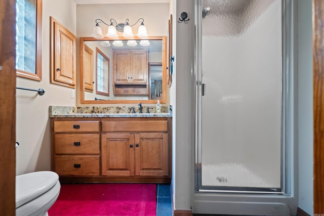 bathroom with toilet, vanity, and a stall shower