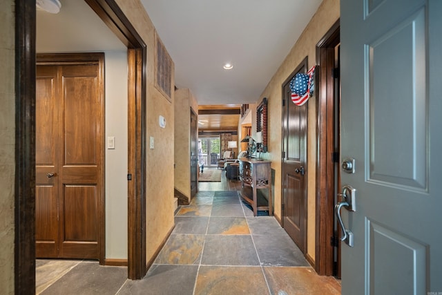corridor with baseboards, stone finish flooring, and recessed lighting