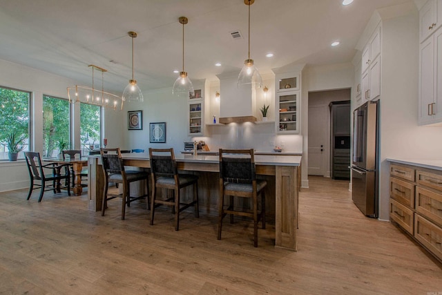 4941 Lake Vista Dr, Benton, AR 72019 - kitchen with high quality fridge, visible vents, premium range hood, a kitchen island with sink, and a kitchen bar
