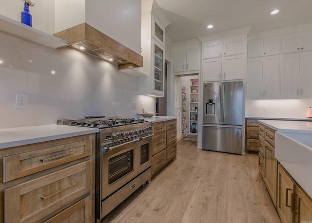 4941 Lake Vista Dr, Benton, AR 72019 - kitchen with custom exhaust hood, light wood finished floors, light countertops, white cabinets, and appliances with stainless steel finishes