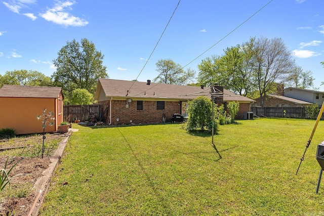 15 Falcon Dr, Sherwood, AR 72120 - back of property with a storage shed, a lawn, a fenced backyard, an outbuilding, and brick siding