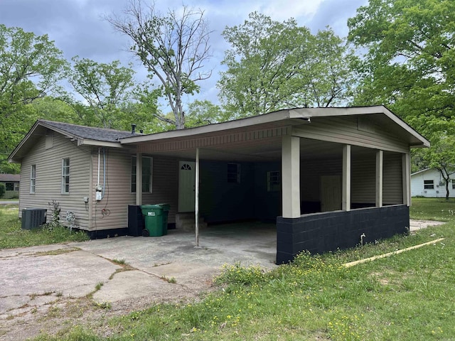 view of side of property featuring an attached carport, central air condition unit, and concrete driveway