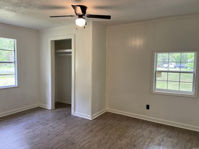 unfurnished bedroom with a textured ceiling, dark wood-style floors, and multiple windows