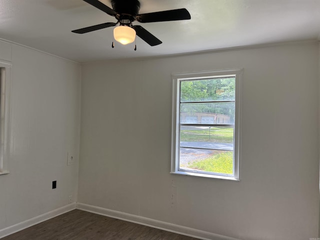 spare room featuring baseboards, a ceiling fan, dark wood-style floors, and ornamental molding