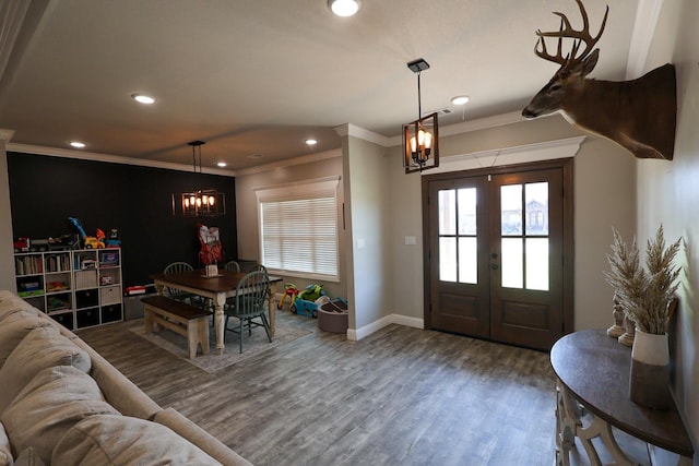 foyer entrance with french doors, baseboards, a notable chandelier, wood finished floors, and ornamental molding