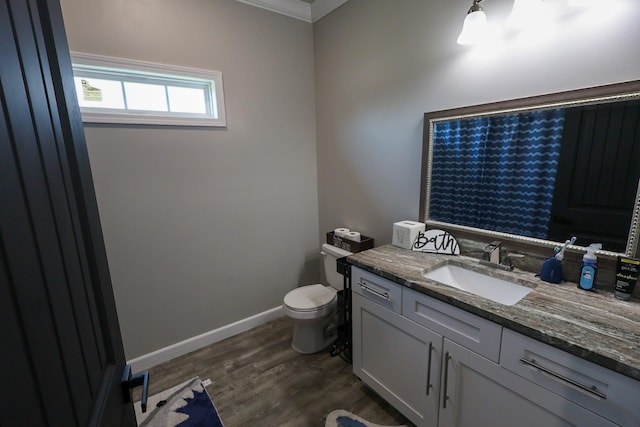 bathroom with wood finished floors, toilet, vanity, crown molding, and baseboards