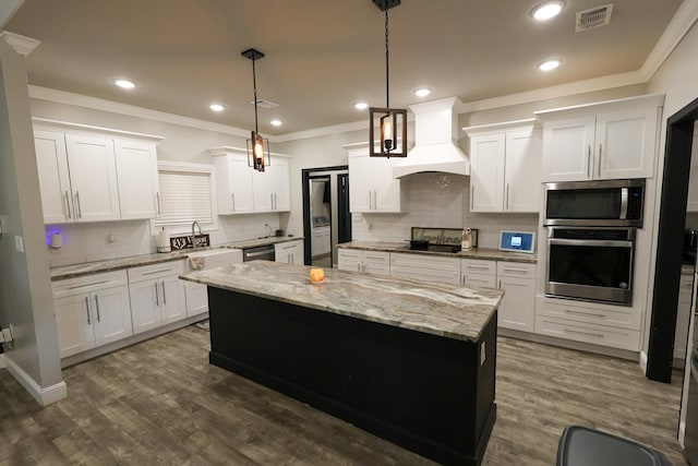 kitchen featuring visible vents, a center island, tasteful backsplash, appliances with stainless steel finishes, and custom range hood