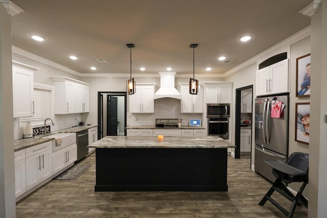 kitchen with a center island, tasteful backsplash, a sink, premium range hood, and appliances with stainless steel finishes