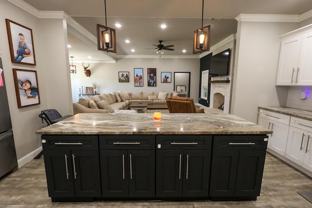 kitchen with white cabinetry, dark cabinetry, wood finished floors, ceiling fan, and crown molding