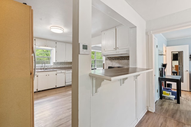 7803 Ascension Rd, Little Rock, AR 72204 - kitchen with white cabinets, backsplash, white dishwasher, and light wood finished floors