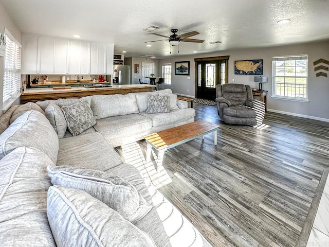 living room featuring recessed lighting, wood finished floors, visible vents, a ceiling fan, and baseboards