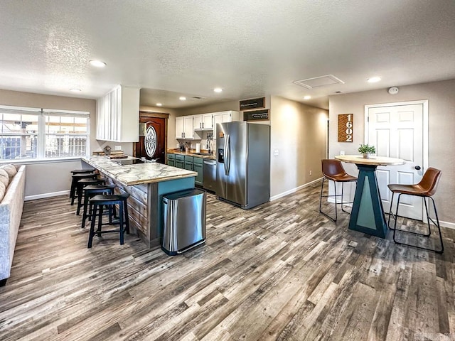 kitchen with stainless steel appliances, a breakfast bar, baseboards, and dark wood-style floors