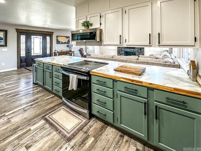 kitchen with green cabinetry, appliances with stainless steel finishes, and light wood-type flooring