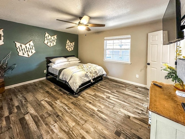 bedroom featuring wood finished floors, a textured ceiling, baseboards, and ceiling fan