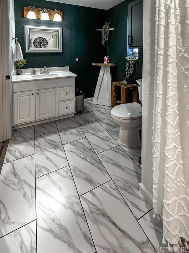 bathroom with marble finish floor, toilet, and vanity