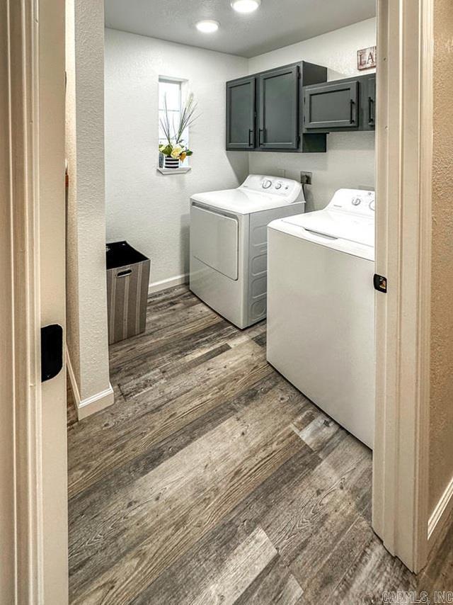 laundry room with washer and clothes dryer, baseboards, cabinet space, a textured wall, and dark wood-type flooring