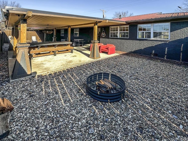 rear view of property with brick siding, a patio area, a fire pit, and fence