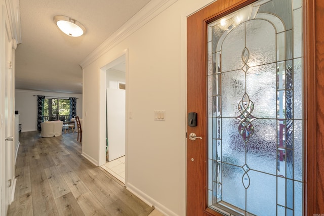 foyer featuring baseboards, crown molding, and light wood-type flooring