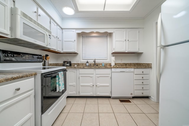kitchen featuring white cabinets, light tile patterned floors, a sink, white appliances, and stone counters