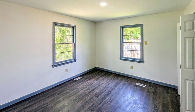 spare room featuring visible vents, a wealth of natural light, and dark wood-style flooring